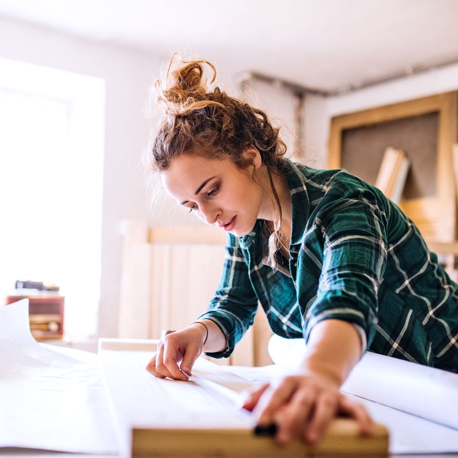 Small business owner measuring wood in her workshop